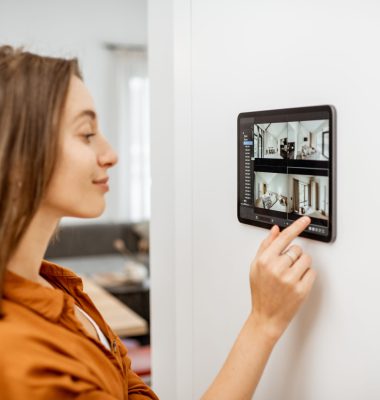 Young woman watching video from security cameras on a digital tablet at home. Concept of remote video surveillance over the internet with smart devices