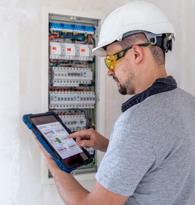 Man, an electrical technician working in a switchboard with fuses. Installation and connection of electrical equipment.