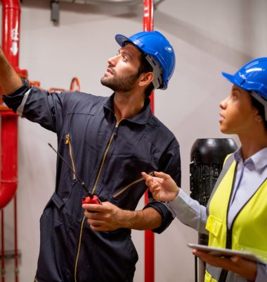 Two engineer or technician worker discuss about red pipe system in the construction site to maintenence and fix the problem together.